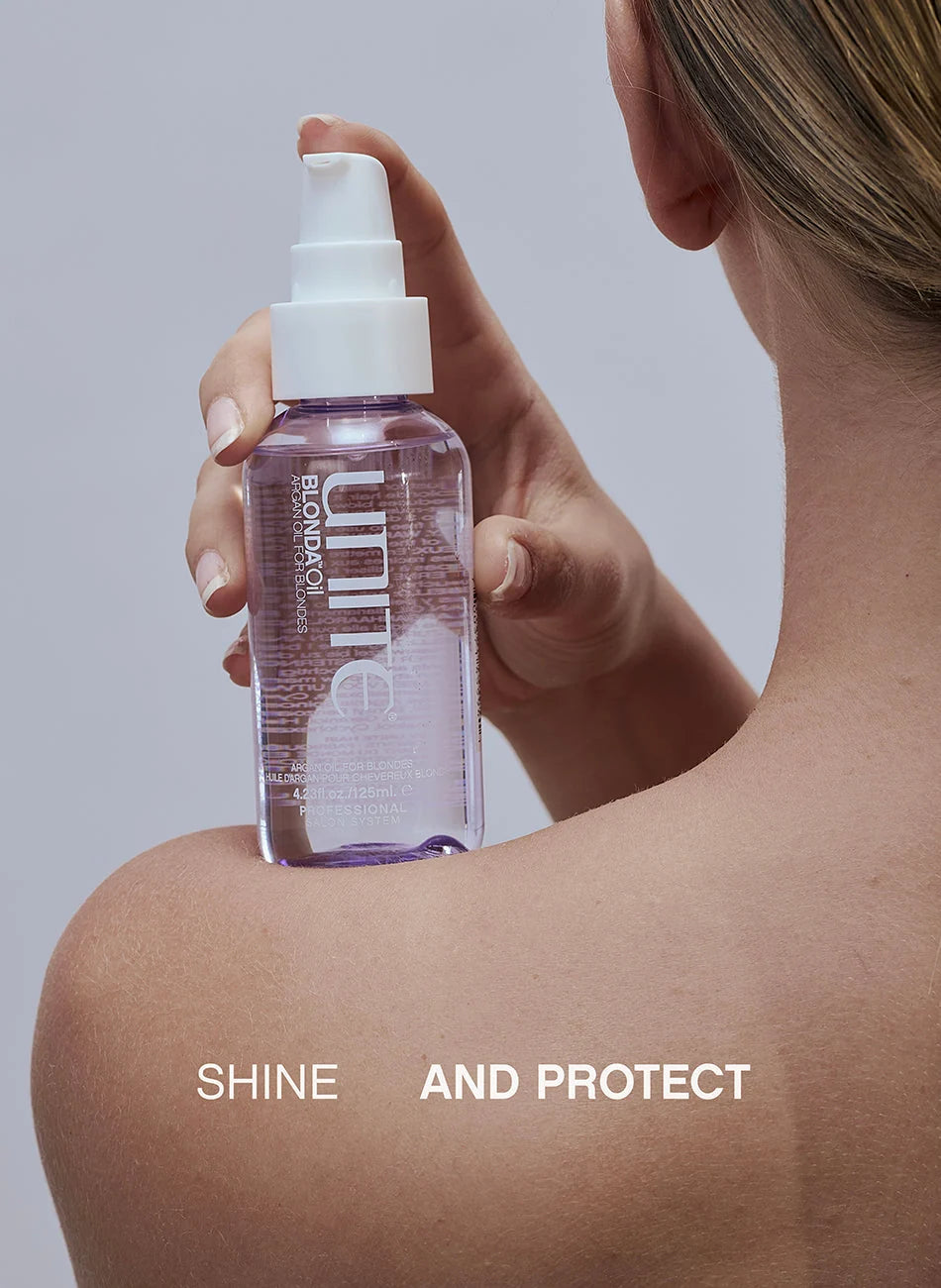 A woman shown from the back holds a clear spray bottle with a white pump dispenser against her shoulder. The bottle contains a light purple liquid and has visible branding that reads 'UNIQ' and 'SEKIRO'.