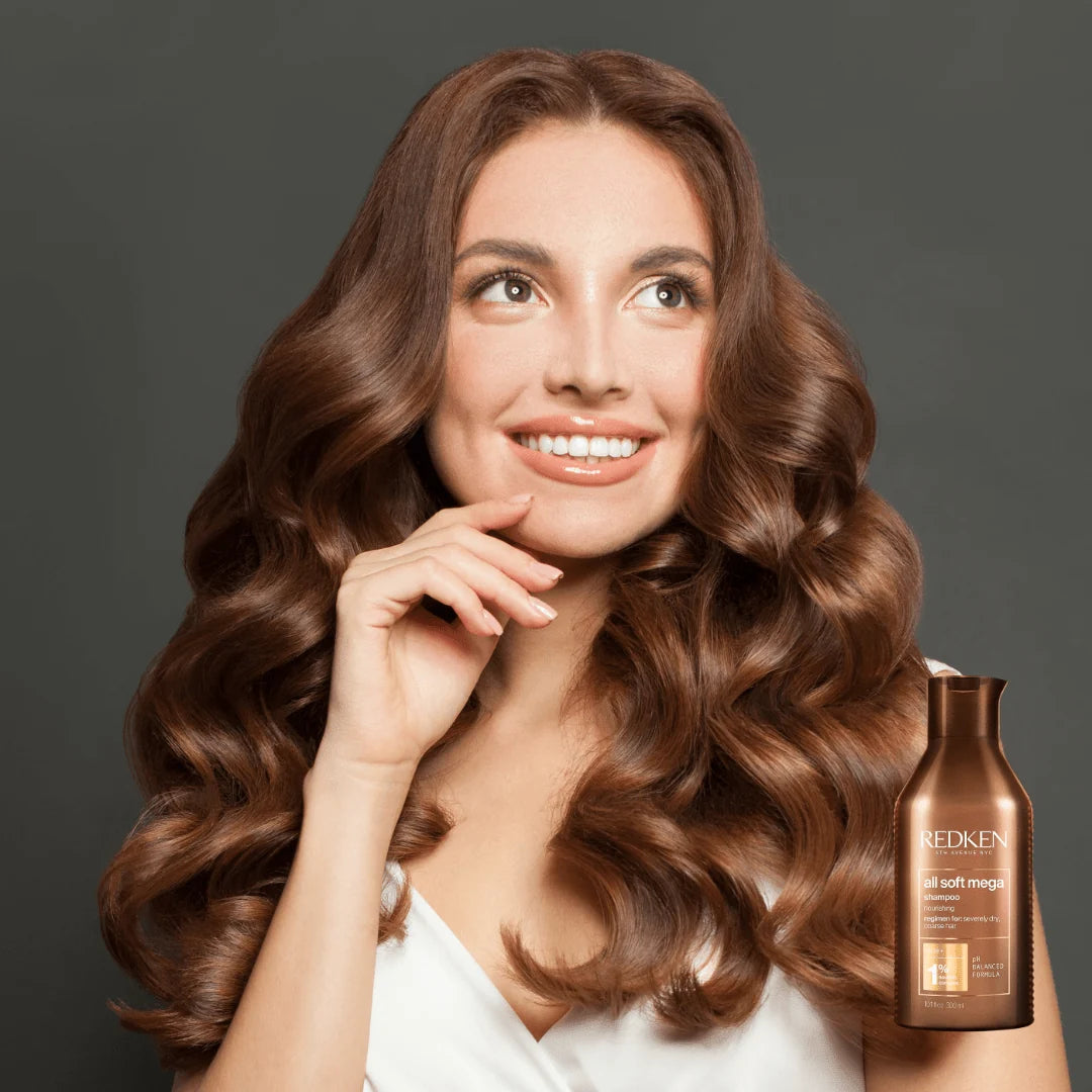 Woman with long, wavy hair next to a bottle of Redken hair product on a dark background