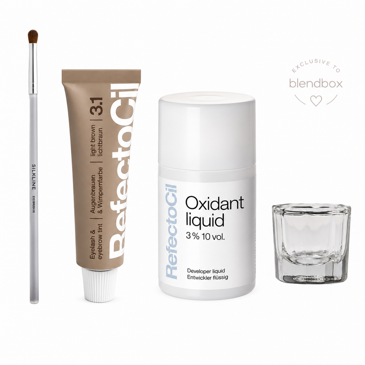 A beauty gift set from ReflectoOil on a white background, including a light brown eyeshadow tube, a small makeup brush, a white developer liquid bottle, and an empty clear glass cup. A 'EXCLUSIVE TO blendbox' badge is visible in the top right.