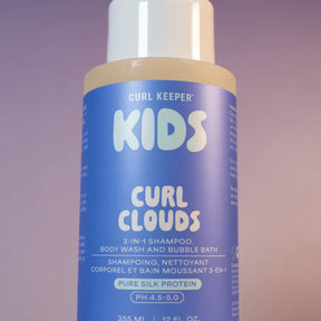A bottle of Curl Keeper Kids Curl Clouds 3-in-1 shampoo, body wash, and bubble bath. The bottle has a white cap, beige plastic at the neck, and a blue label with white text.