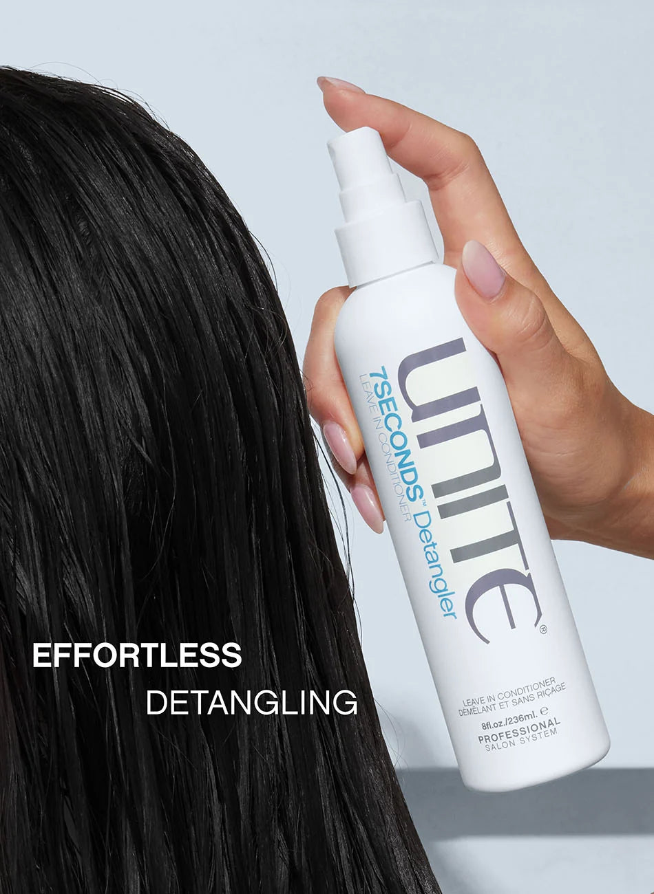 A hand holding a white bottle of Unite 7 Seconds Detangler spray next to long, dark, wet hair, with the text 'EFFORTLESS DETANGLING' on the left.