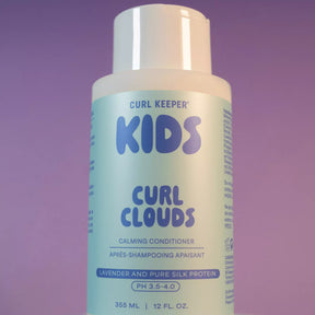 A bottle of Curl Keeper Kids Curl Clouds Calming Conditioner, featuring a white cap and a light blue label with purple text, set against a solid purple background.