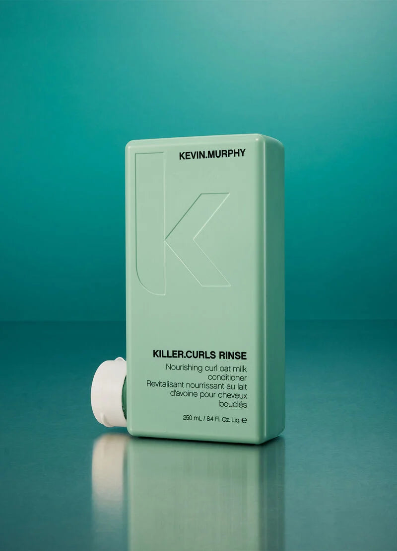 Kevin Murphy Killer Curls Rinse nourishing curl oil milk conditioner in a light mint green rectangular bottle with a white cap, set against a teal gradient background with a reflection below.