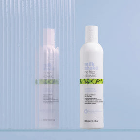 Two bottles of 'milk shea' hair care products on a light blue background
