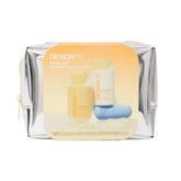 DesignMe Curl Kit in a metallic silver zippered pouch with a large yellow-orange label showing the included bottles and a blue curling tool, on a white background.