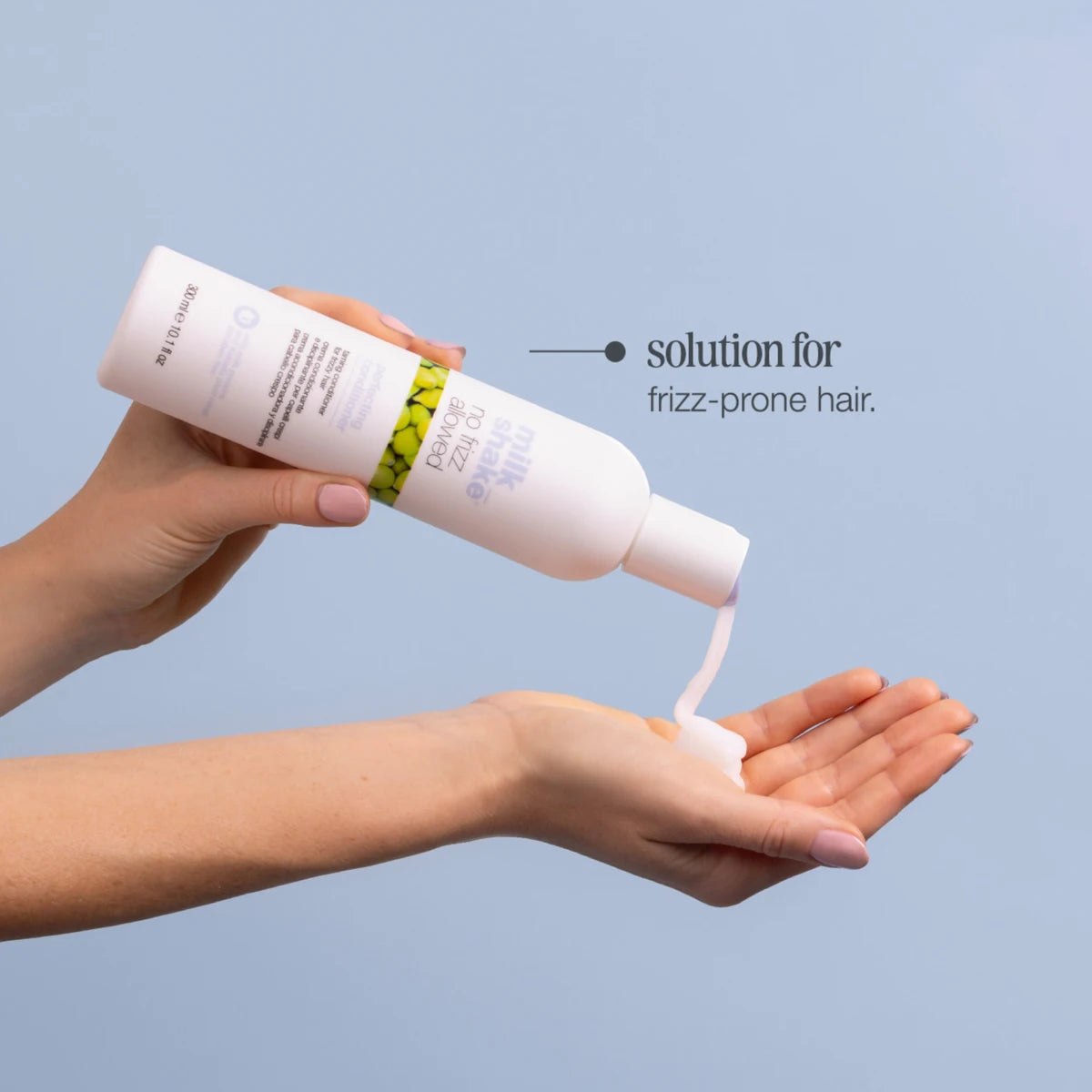 Hand holding a bottle of hair care product with text 'solution for frizz-prone hair' on a light blue background