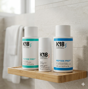 Three K18 hair care products on a wooden shelf against a tiled bathroom wall.