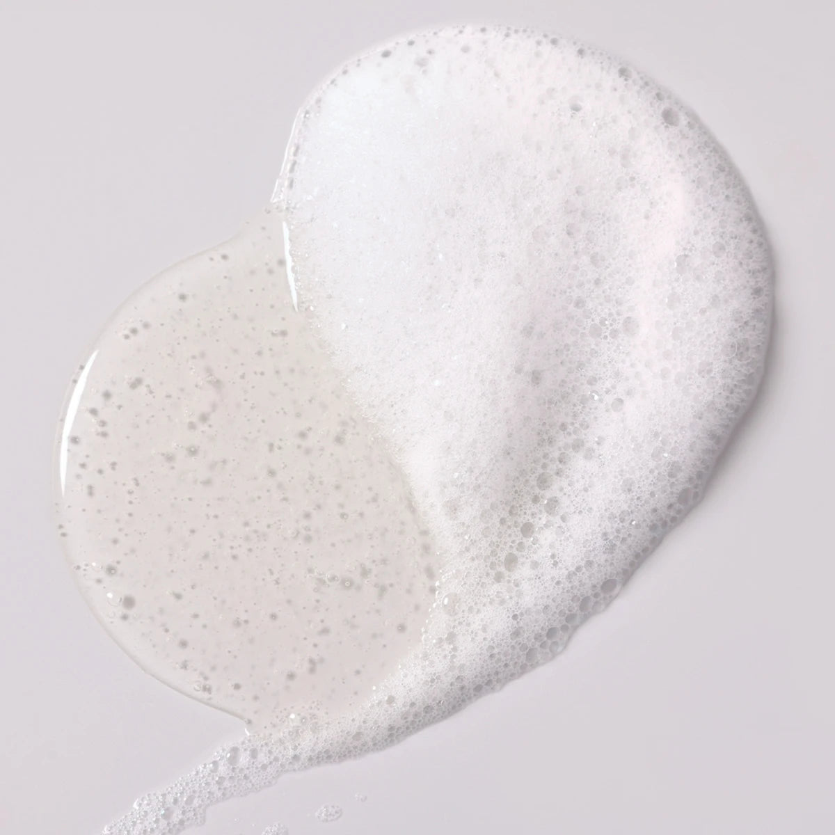 White cream or soap with glitter on a light gray background