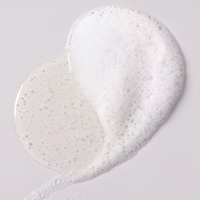 White cream or soap with glitter on a light gray background