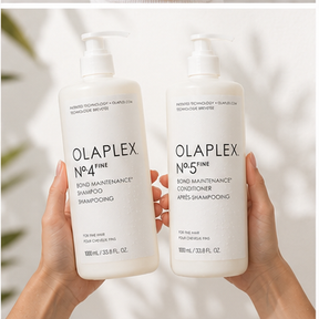 Two hands holding white pump bottles of OLAPLEX No.4 Fine Bond Maintenance Shampoo and No.