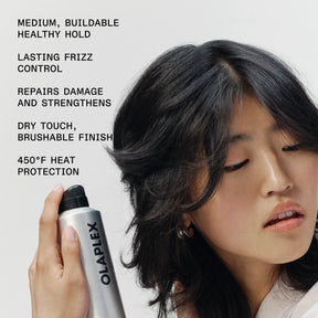 A woman with long black hair holds an Olaplex hair product canister against a light gray background, with product benefits listed in black text on the left side.