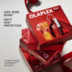 Olaplex No. 7 Bonding Oil gift set in red packaging, with multiple boxes stacked and a ribbon, plus product text on a light gray background.