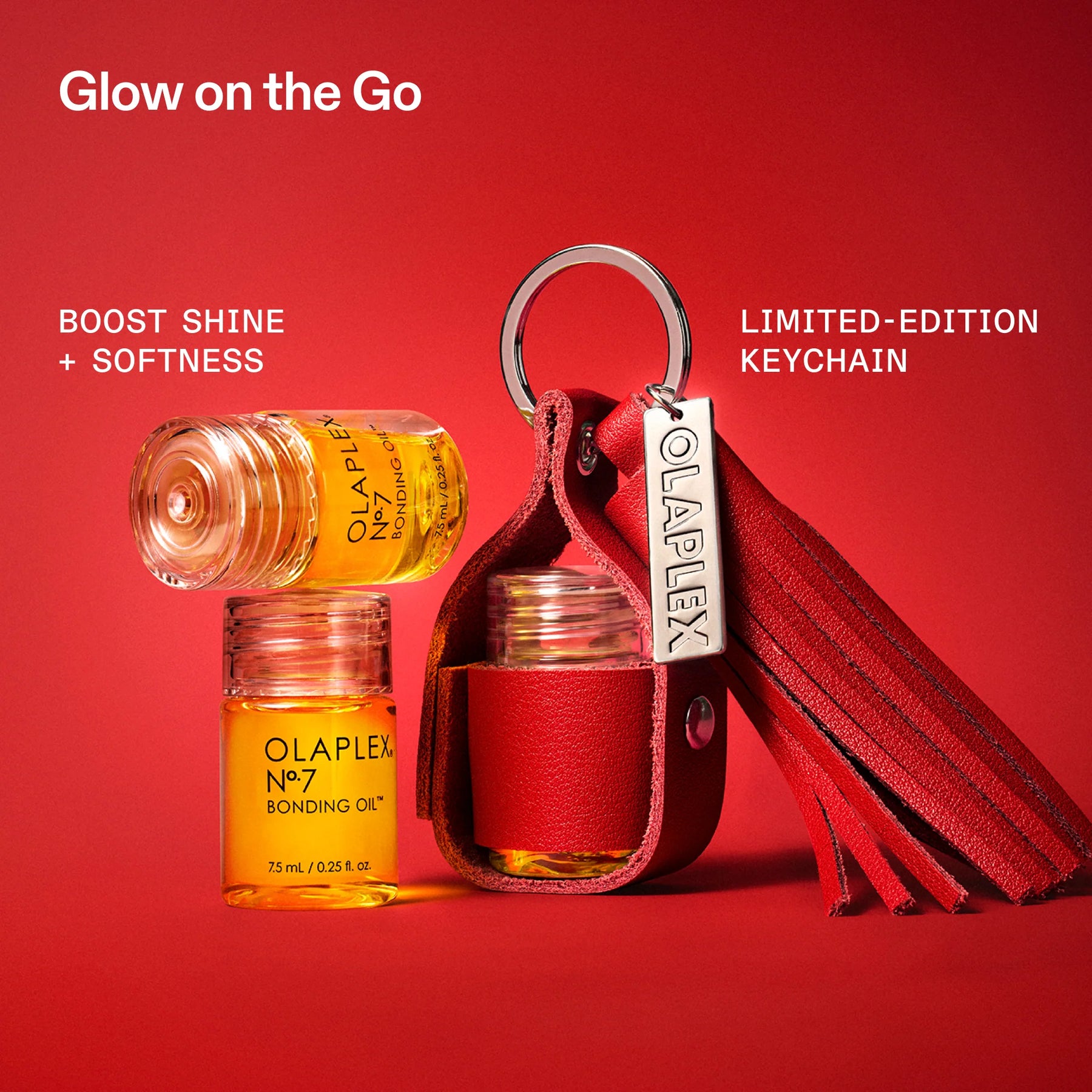 A red leather keychain pouch with a silver metal ring and a branded Olaplex tag, shown alongside two small amber bottles of Olaplex No. 7 Bonding Oil on a solid red background.