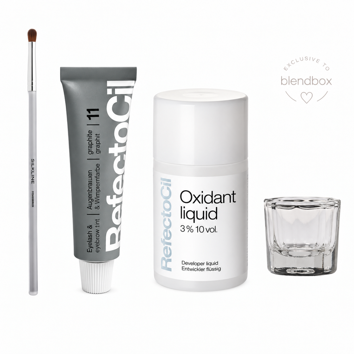 ReflectoOil eyelash and eyebrow development kit on a white background, including a gray tube of pigment, a white developer liquid bottle, a clear glass mixing cup, and a white eye brush, with a Blendbox exclusive badge.