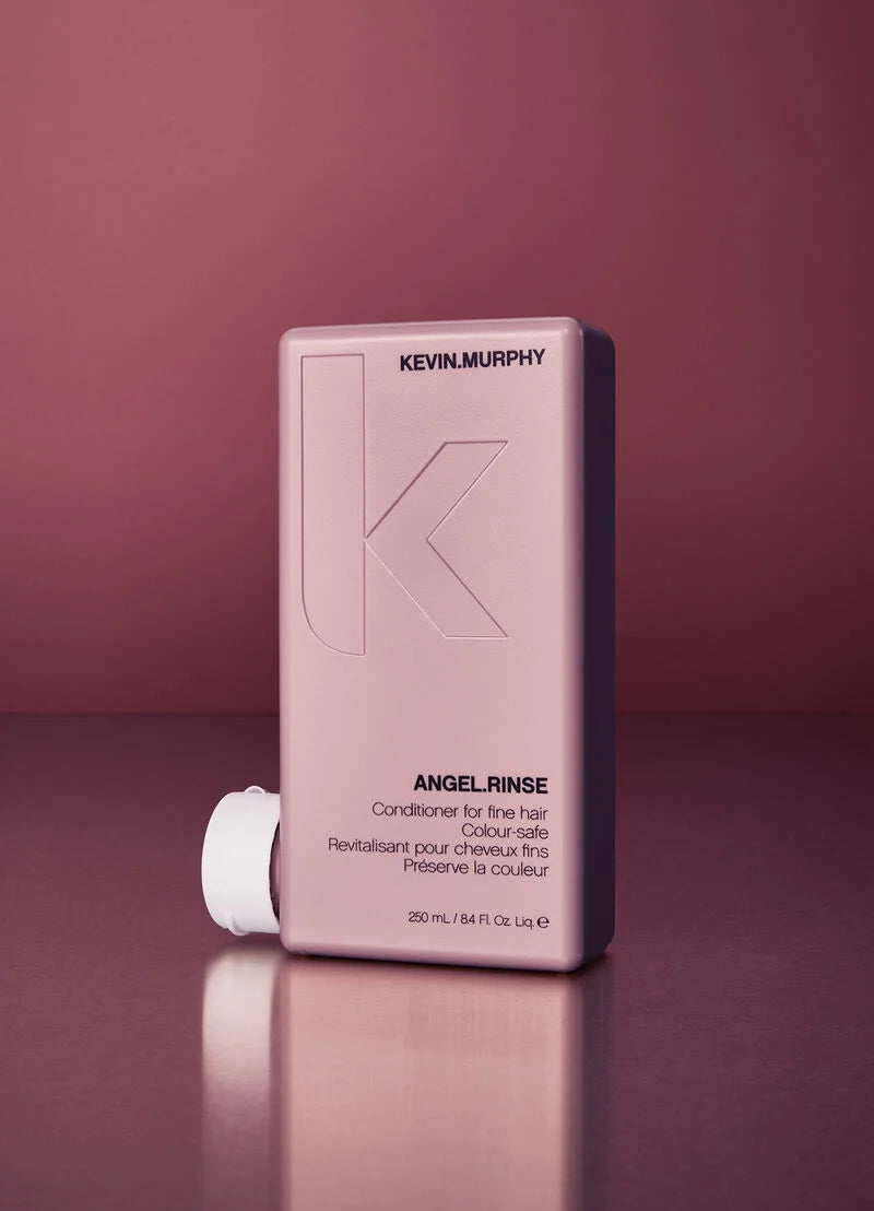 Kevin Murphy Angel Rinse conditioner for fine hair in a rectangular pale pink bottle with a white cap, set against a matching dusty rose background.